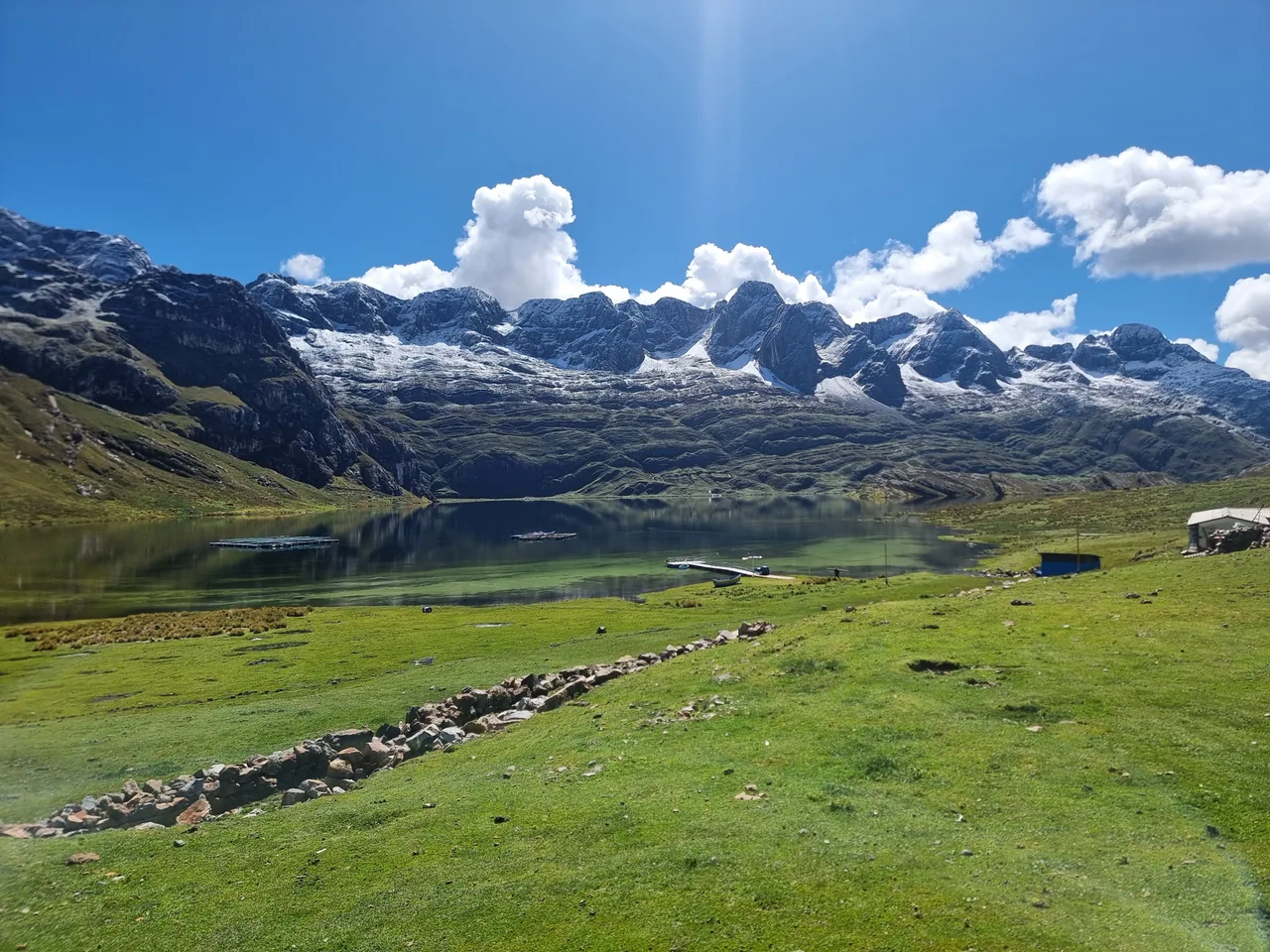 Vista panorámica de Laguna Canrash con laguna, muelle, casitas y nevados
